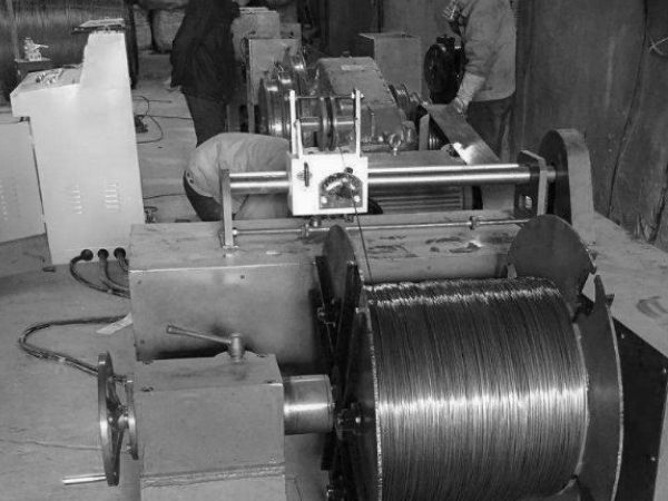 wo workers are operating wire drawing machine.