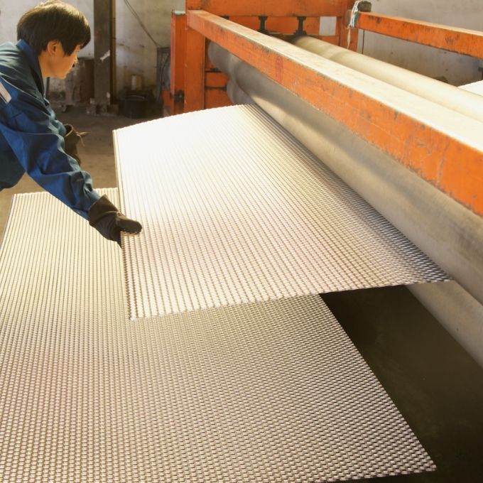 A worker is receiving expanded metal out of the leveling machine.