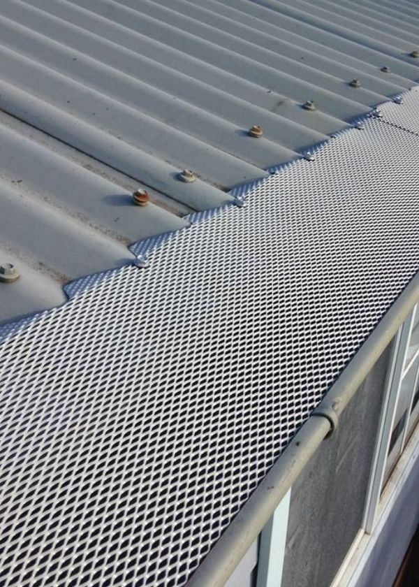 Expanded metal gutter guards are installed at the edge of roof eaves.
