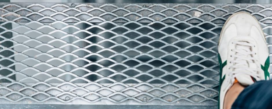 A man is stepping onto the expanded metal grating stair tread.