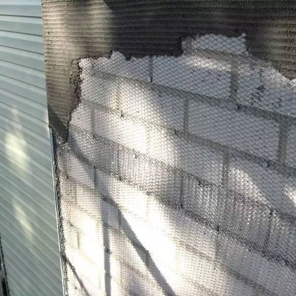 Stucco is applied on the expanded metal lath secured onto the brick wall.