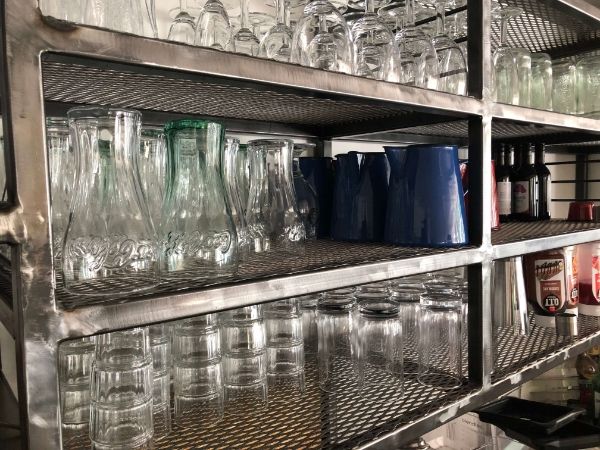 Many glass bottles are placed on the expanded metal shelf decking.