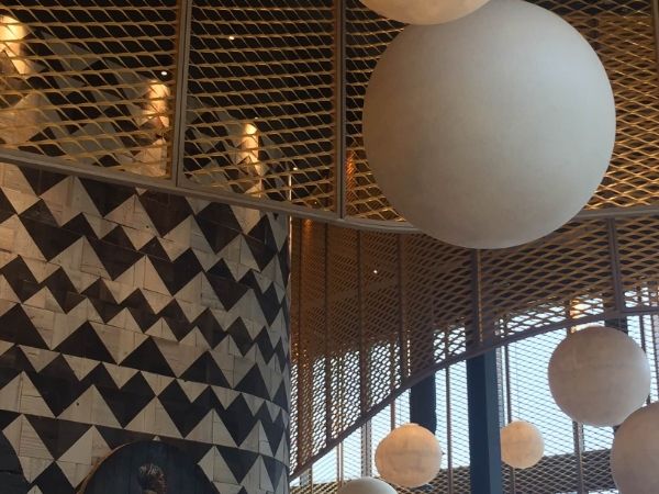 Golden expanded metal sheets are hanging from the ceiling.