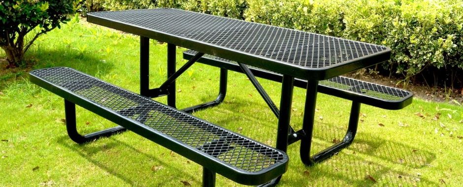 Black flattened expanded metal fabricated outdoor desk and chairs are placed on the grassland.