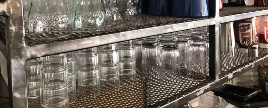 Many glass containers are placed on the expanded metal shelf decking.