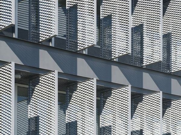 Many sliver expanded metal sunshades are installed outside the window.