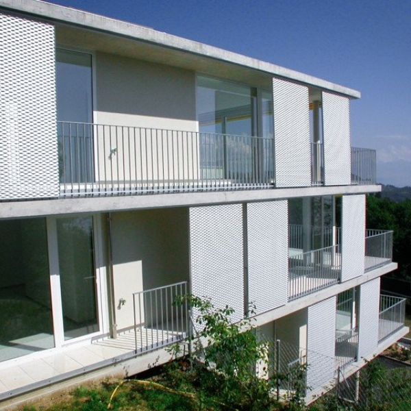White expanded metal sunshades are installed outside the glass window.